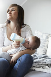 Young mother bottle-feeding baby at home - STKF001244