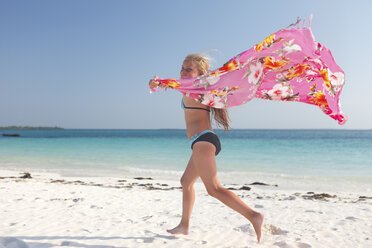 Tansania, Insel Sansibar, Mädchen mit Tuch läuft am Strand am Meer - HR000023