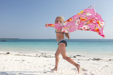 Tanzania, Zanzibar Island, girl with cloth running on the beach at seafront - HR000023