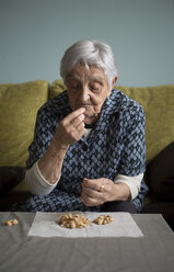 Ältere Frau isst Pistazien zu Hause - RAEF000186