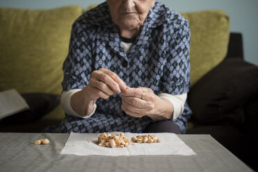 Ältere Frau isst Pistazien zu Hause - RAEF000187