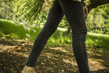 Frau geht mit Blumen im Park spazieren - RIBF000065