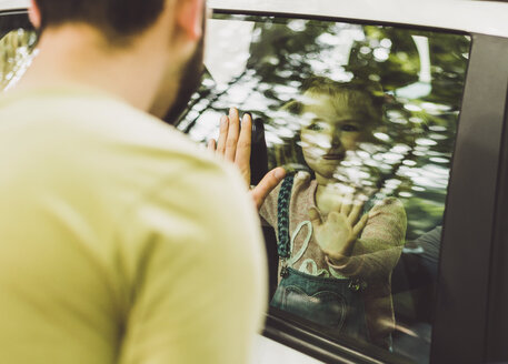 Mädchen im Auto schaut Vater hinter der Fensterscheibe an - UUF004254