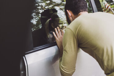 Mädchen im Auto schaut Vater hinter der Fensterscheibe an - UUF004259