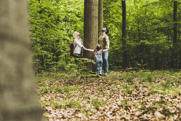 Family in forest standing around tree trunk looking up - UUF004268