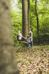 Familie im Wald steht um einen Baumstamm herum und schaut nach oben - UUF004269