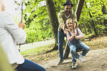 Glückliches Mädchen mit Vater und Mutter auf dem Spielplatz - UUF004275