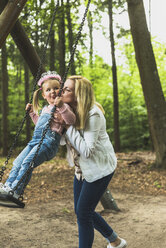 Mother holding happy daughter on swing - UUF004278