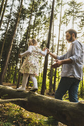 Father helping girl balancing on log - UUF004286