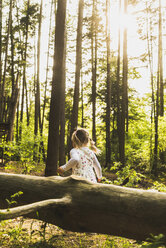 Girl in forest behind log - UUF004290