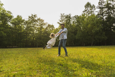 Father turning daughter on meadow - UUF004308