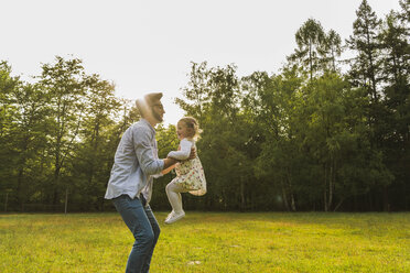 Father lifting up daughter on meadow - UUF004309