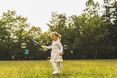 Girl on meadow surrounded by soap bubbles - UUF004319