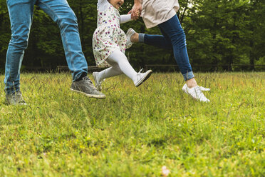 Father, mother and daughter running on meadow - UUF004328