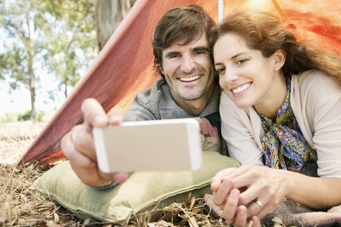 Südafrika, glückliches Paar liegt im Zelt und macht ein Selfie - TOYF000676