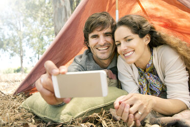 Südafrika, glückliches Paar liegt im Zelt und macht ein Selfie - TOYF000677