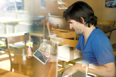 Mann in einem Café mit digitalem Tablet - TOYF000799