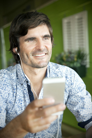 Smiling man listening to music from smartphone stock photo