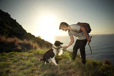 Südafrika, Mann mit Hund an der Küste bei Sonnenuntergang - TOYF000805