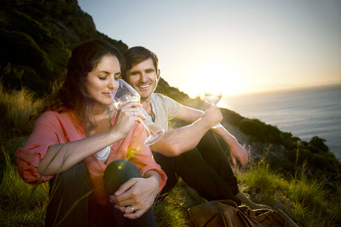 Südafrika, Paar trinkt Weißwein an der Küste bei Sonnenuntergang - TOYF000699