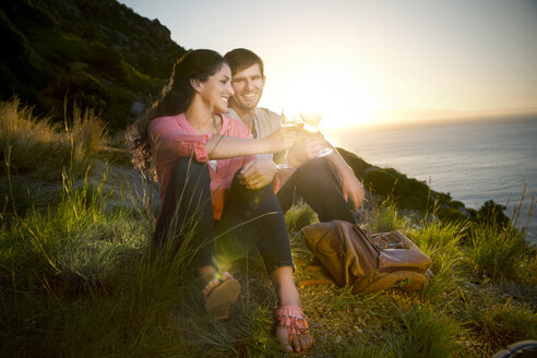 Südafrika, Paar trinkt Weißwein an der Küste bei Sonnenuntergang - TOYF000708