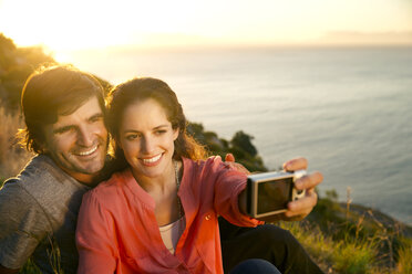 South Africa, couple taking a selfie at the coast at sunset - TOYF000709