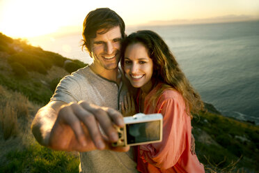 South Africa, couple taking a selfie at the coast at sunset - TOYF000711