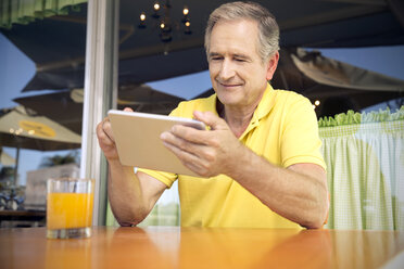 Porträt eines älteren Mannes, der ein digitales Tablet in einem Café benutzt - TOYF000731