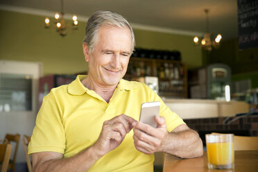 Portrait of senior man using smartphone in a cafe - TOYF000732