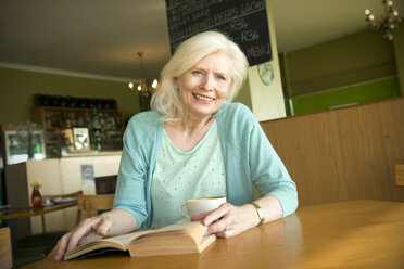 Porträt einer älteren Frau mit Buch in einem Cafe - TOYF000735