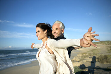 South Africa, couple with outstretched arms standing on the beach looking at distance - TOYF000756