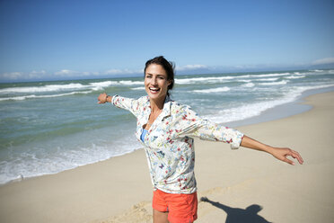 Südafrika, lachende Frau mit ausgestreckten Armen am Strand stehend - TOYF000777