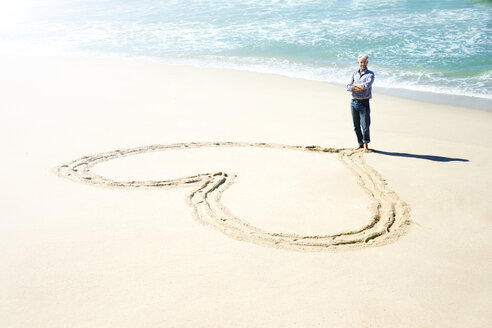 Südafrika, Mann steht vor einem in den Strandsand gemeißelten Herz - TOYF000779