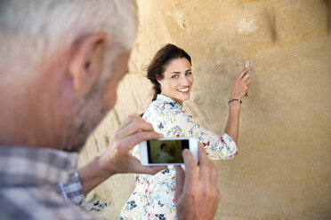 Südafrika, Mann fotografiert seine Frau, die etwas in eine Felswand schnitzt - TOYF000782