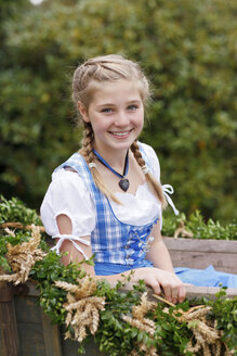 Deutschland, Lüneburger Heide, Porträt eines lächelnden blonden Mädchens im Dirndl auf einem Erntewagen sitzend - HRF000030