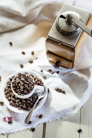 Alte Kaffeemühle und Kaffeetasse gefüllt mit Kaffeebohnen, lizenzfreies Stockfoto