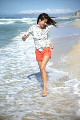 Südafrika, glückliche Frau läuft am Strand entlang - TOYF000794