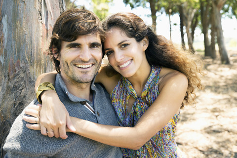 Happy couple in nature with arms around stock photo