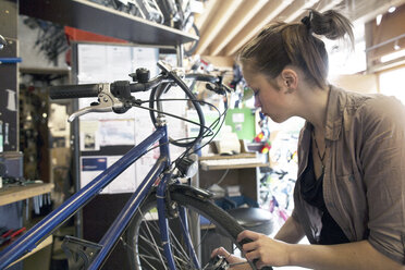 Junge Frau arbeitet in einer Fahrradwerkstatt - SGF001612