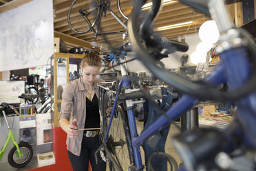 Young woman working in a bicycle repair shop - SGF001620