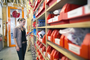 Young woman in storeroom of a bicycle repair shop - SGF001602