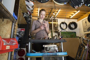 Young woman working in a bicycle repair shop - SGF001605