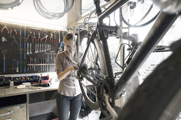 Junge Frau arbeitet in einer Fahrradwerkstatt - SGF001618