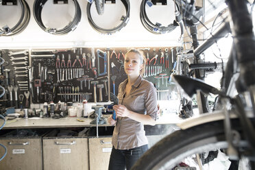 Junge Frau arbeitet in einer Fahrradwerkstatt - SGF001615