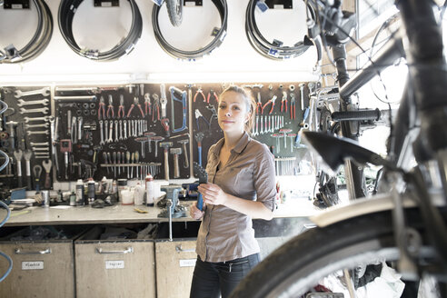 Junge Frau arbeitet in einer Fahrradwerkstatt - SGF001615