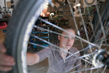 Junge Frau arbeitet in einer Fahrradwerkstatt - SGF001610