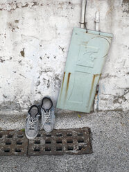 Taiwan, ein Paar Schuhe auf einem Gullydeckel und eine alte Metalltür, die an einer Wand lehnt - JMF000346