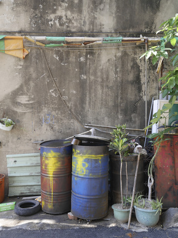 Taiwan, Topfpflanzen und alte Ölfässer in einem Innenhof, lizenzfreies Stockfoto