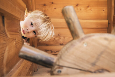 Kleiner Junge schaut durch ein Loch im Holzschiff auf dem Spielplatz - MFF001627