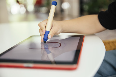 Hand eines Kindes, das einen Brief mit einem digitalen Stift auf einem digitalen Tablet zeichnet, lizenzfreies Stockfoto